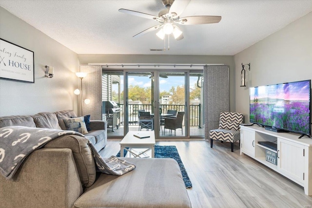 living room featuring ceiling fan, a textured ceiling, light wood-type flooring, and french doors