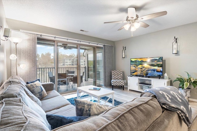 living room with light wood-type flooring, a textured ceiling, and ceiling fan