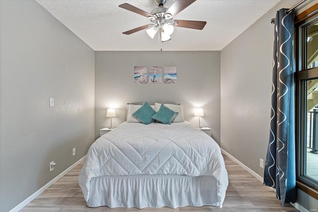 bedroom featuring light hardwood / wood-style floors, ceiling fan, and a textured ceiling