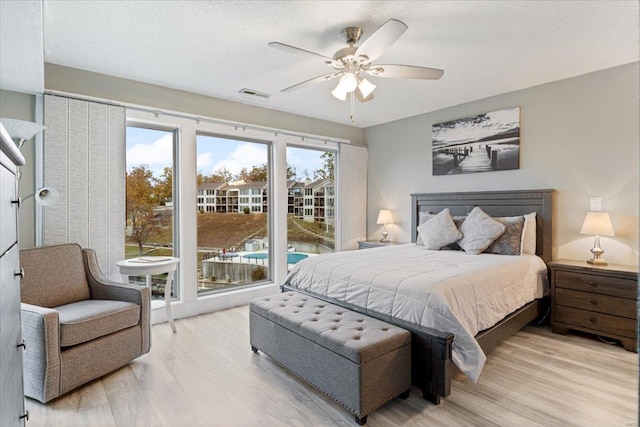 bedroom featuring a textured ceiling, access to outside, light hardwood / wood-style flooring, and ceiling fan