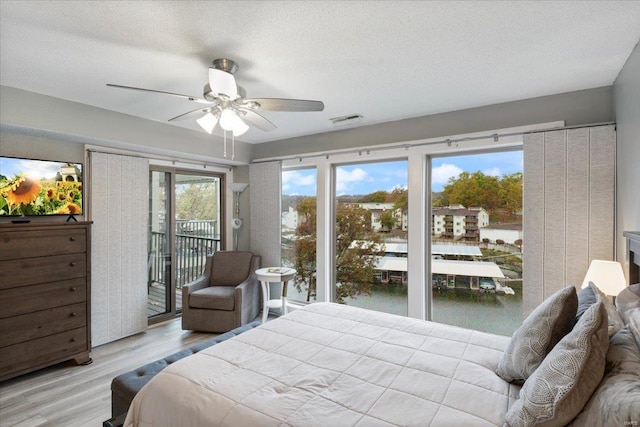 bedroom with ceiling fan, access to exterior, a textured ceiling, and light wood-type flooring