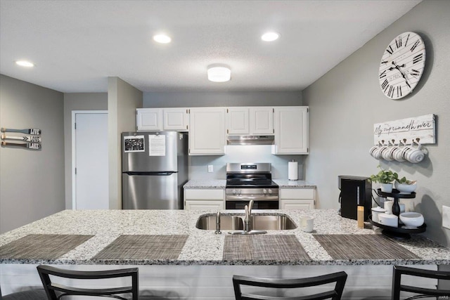 kitchen with stainless steel appliances, a breakfast bar area, white cabinets, and sink