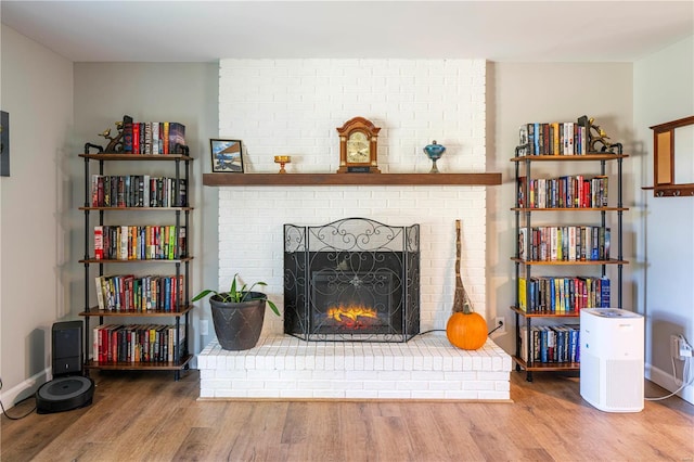 living room with a brick fireplace and hardwood / wood-style flooring