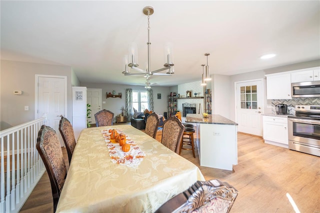 dining space with light wood-type flooring and ceiling fan