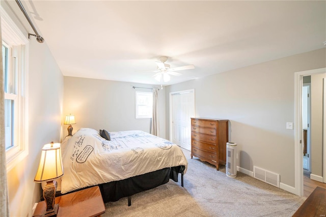 bedroom with light carpet, ceiling fan, and a closet