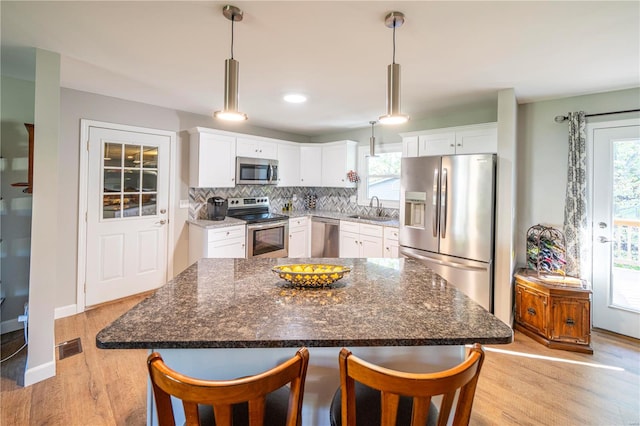 kitchen featuring appliances with stainless steel finishes, a healthy amount of sunlight, white cabinetry, and light hardwood / wood-style floors