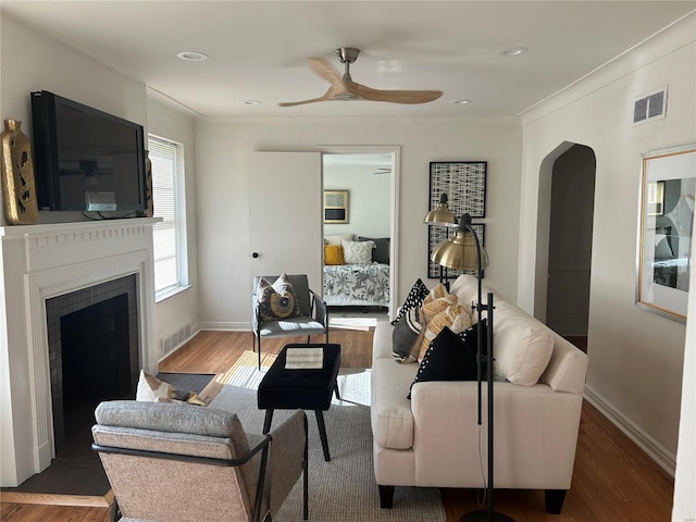 living room featuring dark hardwood / wood-style floors, ceiling fan, and ornamental molding