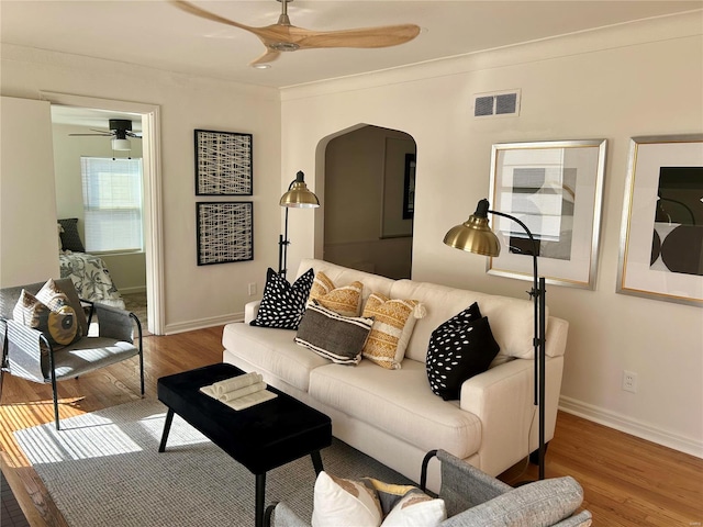 living room with hardwood / wood-style flooring, ceiling fan, and ornamental molding