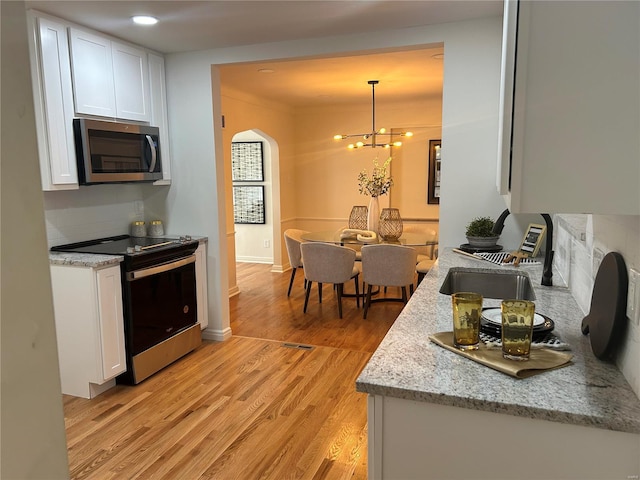 kitchen featuring white cabinets, decorative light fixtures, appliances with stainless steel finishes, and tasteful backsplash