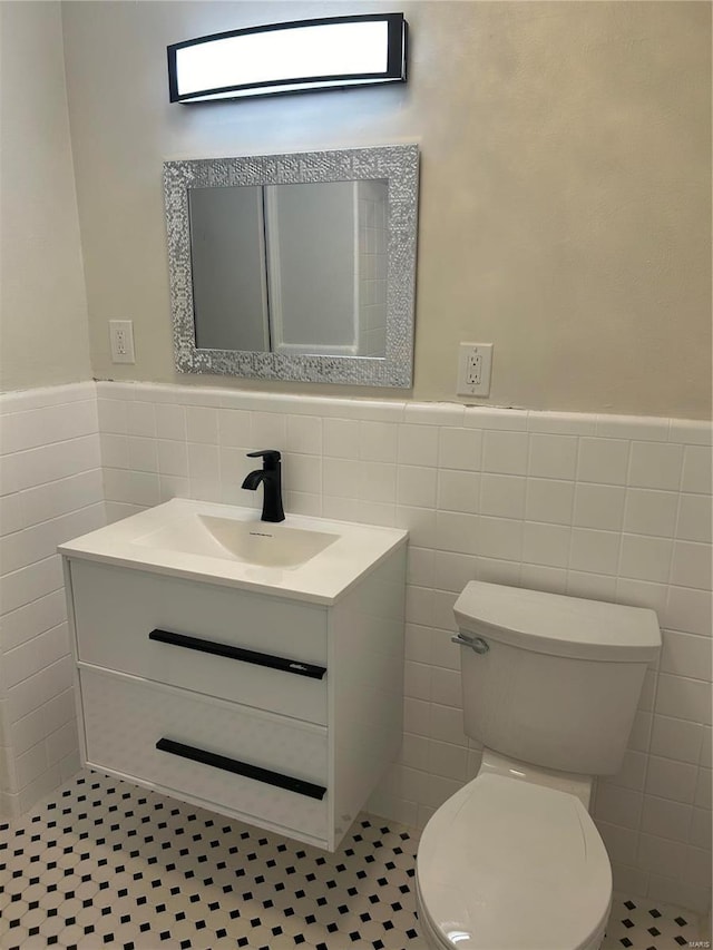 bathroom featuring tile patterned flooring, vanity, toilet, and tile walls