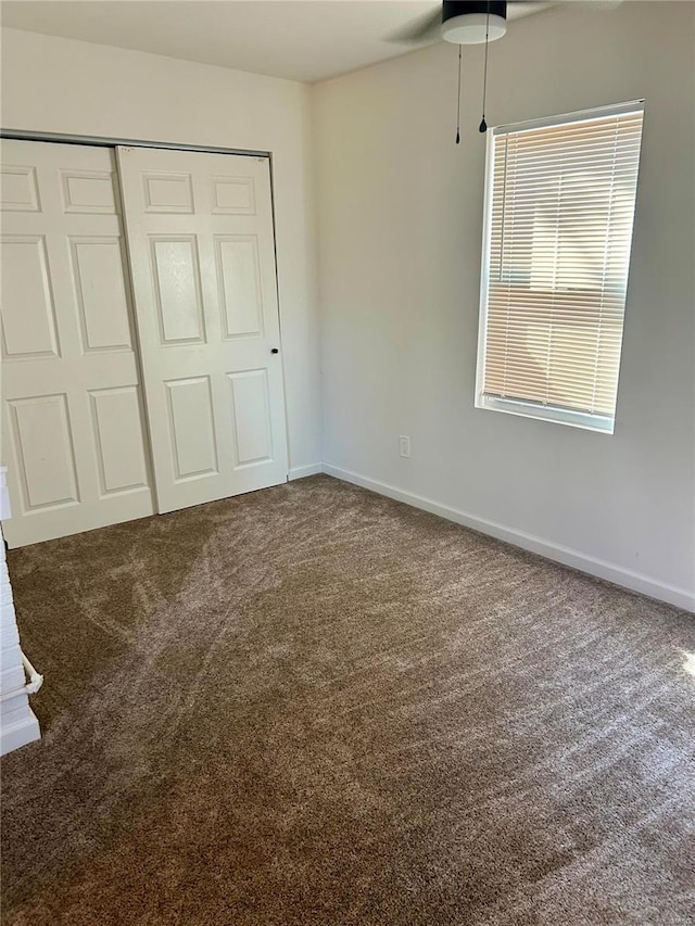 unfurnished bedroom featuring ceiling fan, a closet, and carpet floors