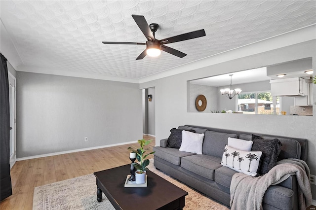 living room with ceiling fan with notable chandelier and light hardwood / wood-style floors