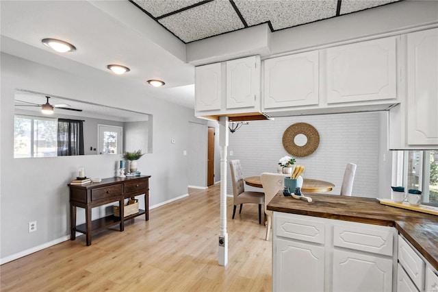 kitchen with ceiling fan, light hardwood / wood-style floors, wooden counters, and white cabinetry