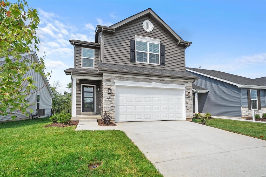 front of property featuring a garage, a front lawn, and central AC unit