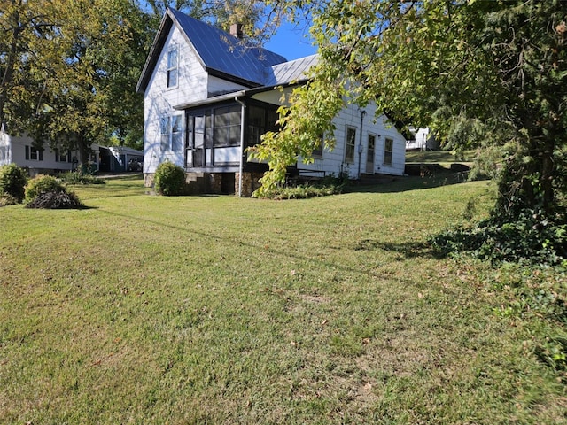 view of property exterior featuring a sunroom and a lawn