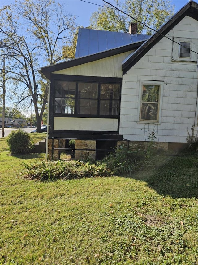 view of side of home featuring a sunroom and a yard