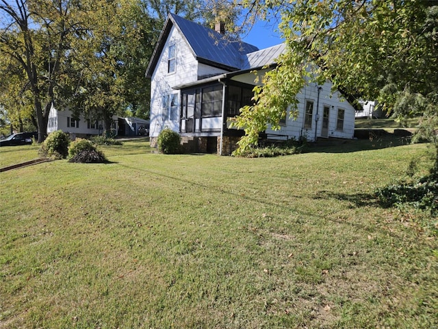 view of side of property with a sunroom and a lawn