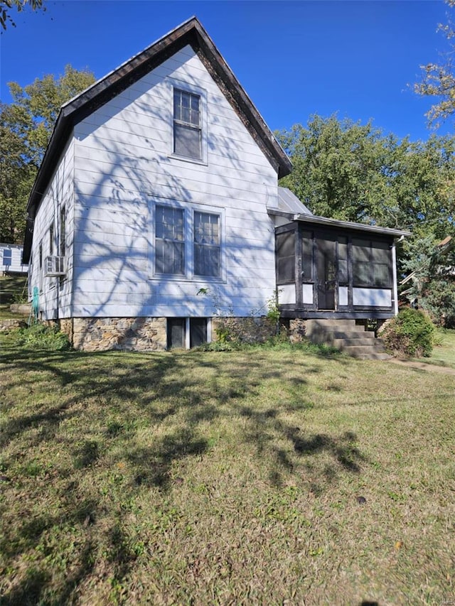 rear view of house with cooling unit, a sunroom, and a lawn