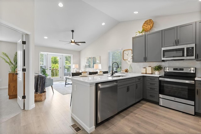 kitchen featuring ceiling fan, sink, kitchen peninsula, gray cabinetry, and appliances with stainless steel finishes