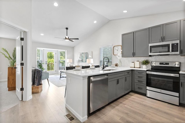 kitchen with gray cabinetry, ceiling fan, sink, kitchen peninsula, and appliances with stainless steel finishes