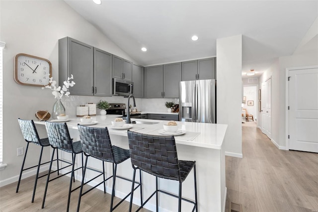 kitchen featuring stainless steel appliances, kitchen peninsula, a kitchen breakfast bar, and light hardwood / wood-style flooring