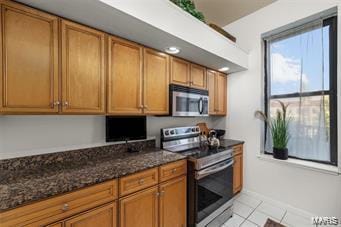 kitchen featuring stainless steel appliances, dark stone counters, and light tile patterned floors