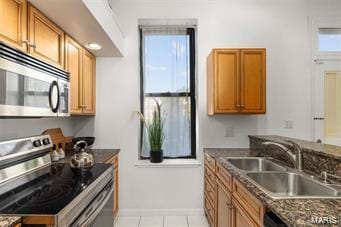 kitchen featuring dark stone counters, appliances with stainless steel finishes, sink, and light tile patterned floors