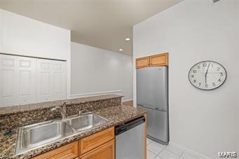 kitchen featuring light tile patterned floors, appliances with stainless steel finishes, sink, and dark stone counters