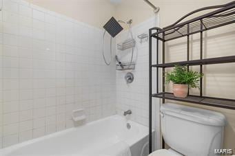 bathroom with tiled shower / bath combo and toilet