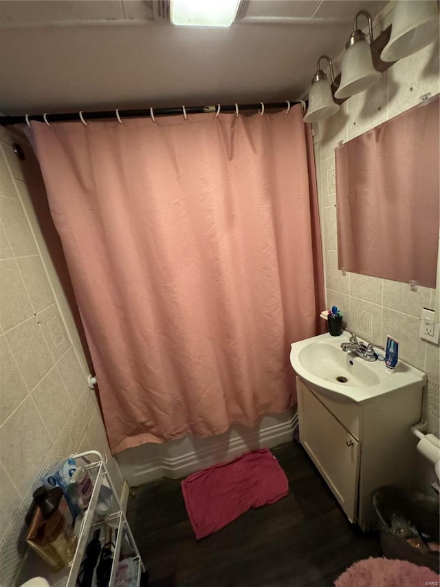 bathroom featuring walk in shower, hardwood / wood-style flooring, vanity, and tile walls