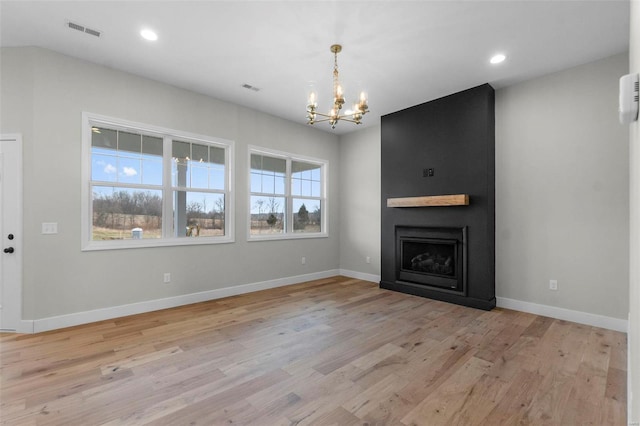 unfurnished living room with a large fireplace, visible vents, baseboards, an inviting chandelier, and light wood-type flooring