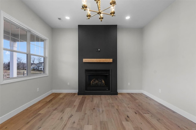 unfurnished living room featuring light wood-type flooring, a large fireplace, visible vents, and baseboards