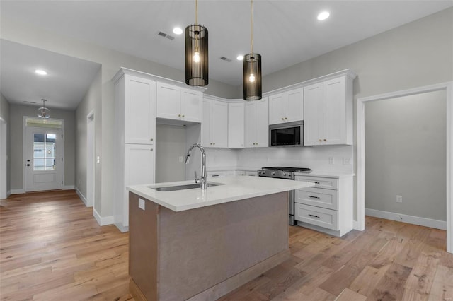 kitchen featuring light wood finished floors, visible vents, appliances with stainless steel finishes, white cabinetry, and a sink