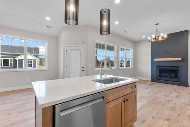 kitchen featuring light wood-style flooring, a fireplace, a sink, open floor plan, and dishwasher