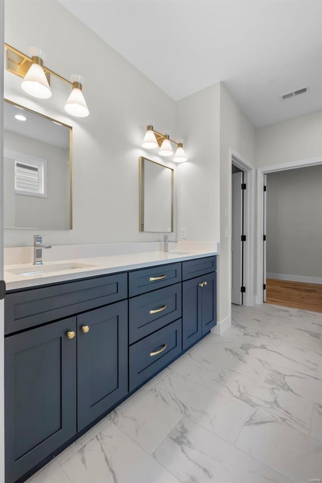 full bath with a sink, visible vents, baseboards, marble finish floor, and double vanity