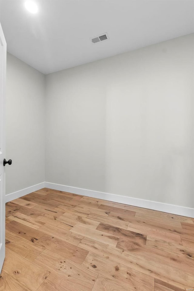 spare room with light wood finished floors, visible vents, and baseboards