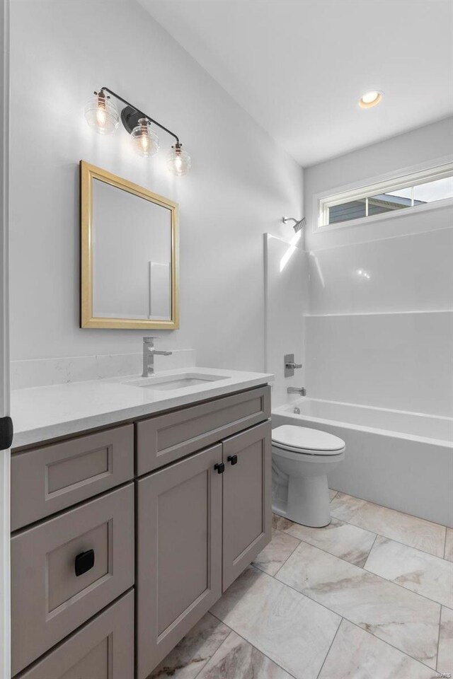 full bathroom featuring washtub / shower combination, marble finish floor, vanity, and toilet