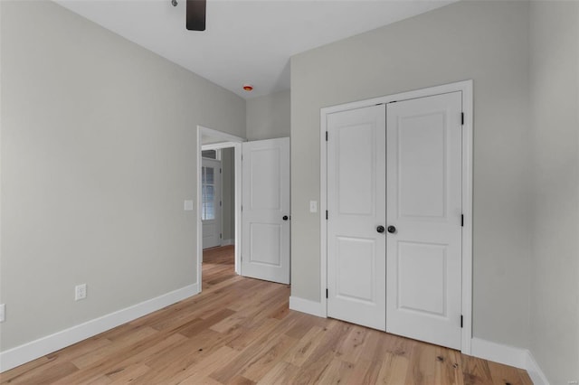 unfurnished bedroom with a closet, ceiling fan, light wood-style flooring, and baseboards