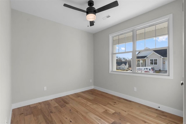 unfurnished room featuring a ceiling fan, baseboards, visible vents, and wood finished floors