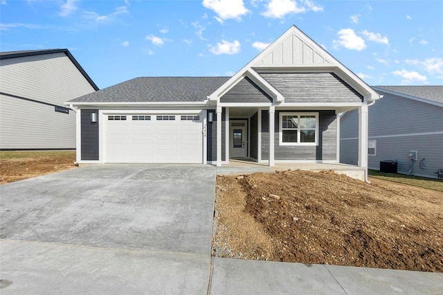 view of front facade featuring a porch, central air condition unit, a garage, driveway, and board and batten siding