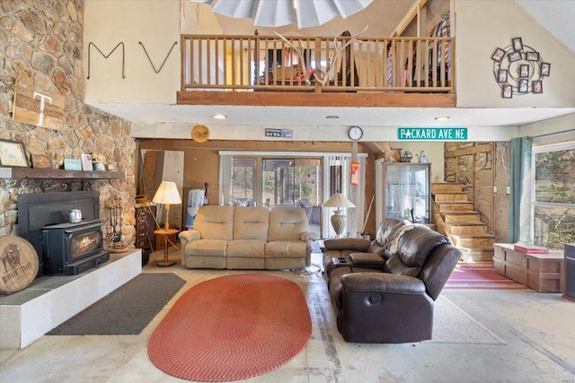 living room featuring concrete floors, high vaulted ceiling, a wood stove, and a healthy amount of sunlight