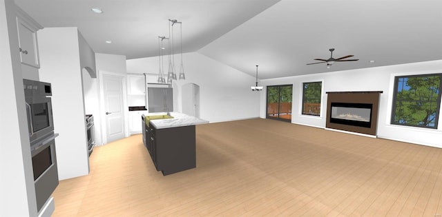 kitchen featuring ceiling fan, decorative light fixtures, lofted ceiling, a kitchen island, and stainless steel oven