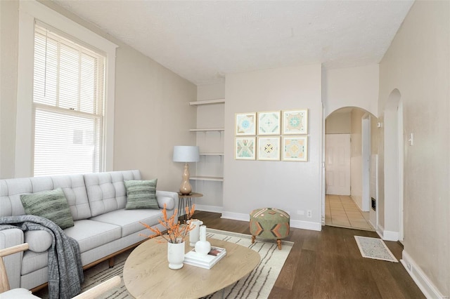 living room featuring built in shelves, a textured ceiling, and dark hardwood / wood-style floors