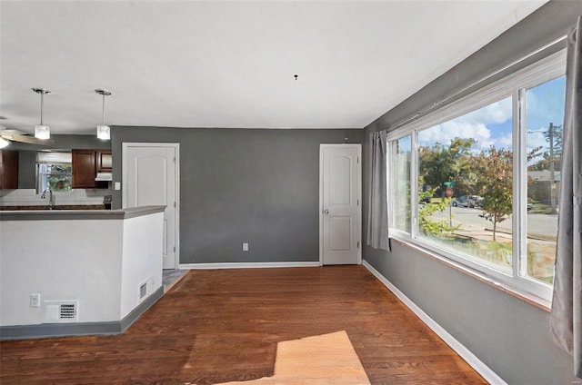 interior space featuring kitchen peninsula, dark hardwood / wood-style flooring, decorative light fixtures, and sink