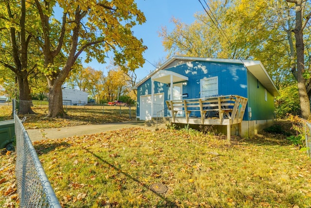 exterior space featuring a wooden deck, a yard, an outdoor structure, and a garage