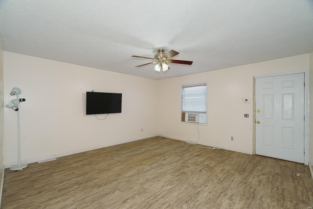 unfurnished living room with ceiling fan, cooling unit, light hardwood / wood-style floors, and a textured ceiling