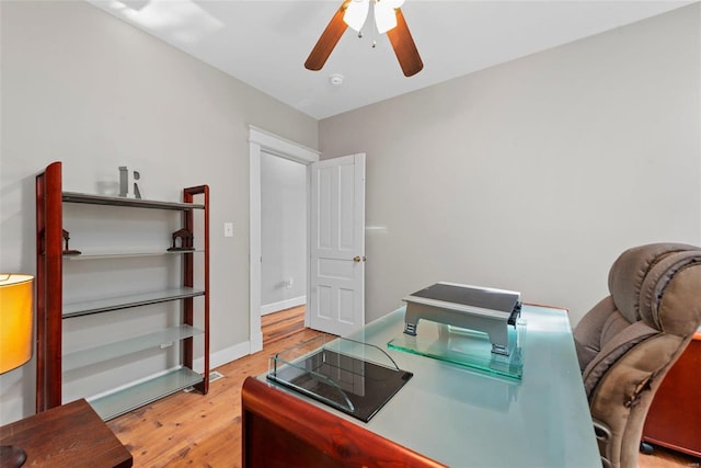 home office with light hardwood / wood-style floors and ceiling fan