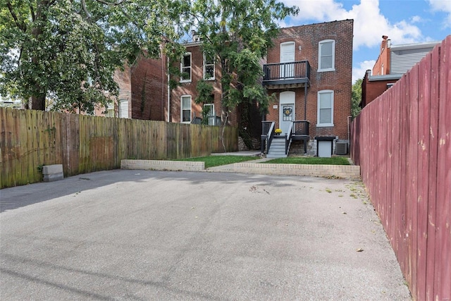 view of front of property with fence private yard, brick siding, and central AC