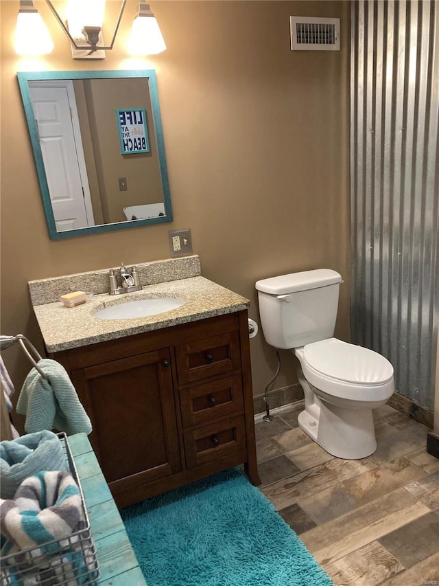 bathroom with vanity, toilet, and hardwood / wood-style flooring