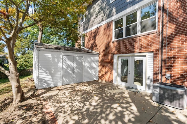 rear view of property with a storage shed, a patio, and central AC